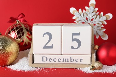 Photo of Block calendar and festive decor on red background. Christmas countdown