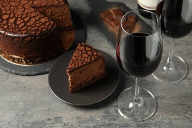Photo of Delicious chocolate truffle cake and red wine on grey textured table