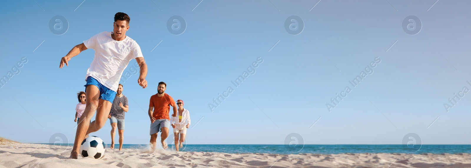 Image of Group of friends playing football on sandy beach, low angle view. Banner design with space for text