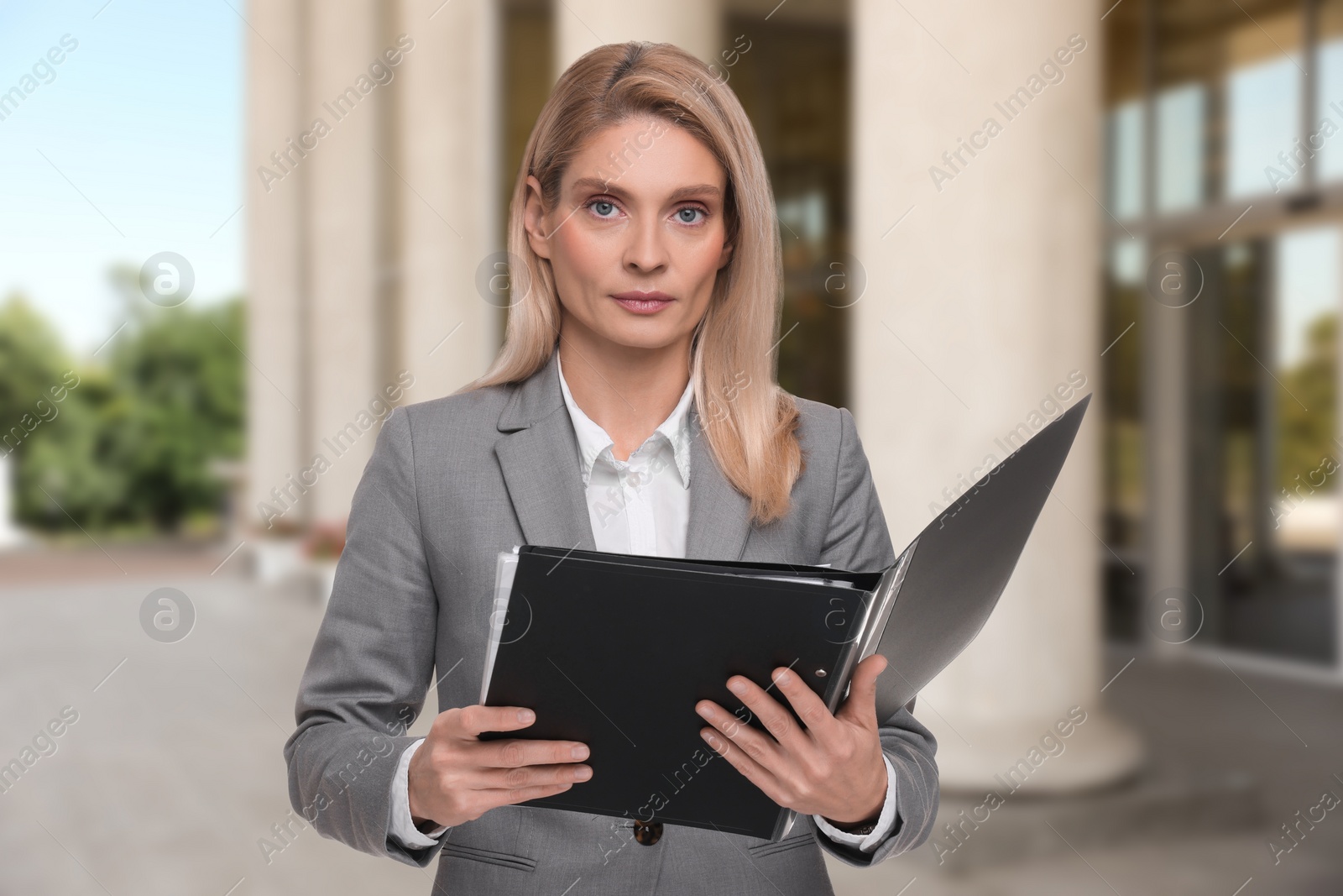 Image of Lawyer, consultant, business owner. Confident woman with file folders outdoors