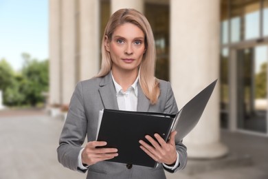 Image of Lawyer, consultant, business owner. Confident woman with file folders outdoors