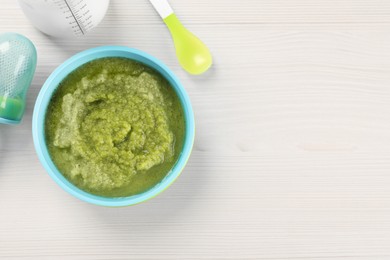 Healthy baby food. Bowl with tasty broccoli puree on white wooden table, flat lay and space for text