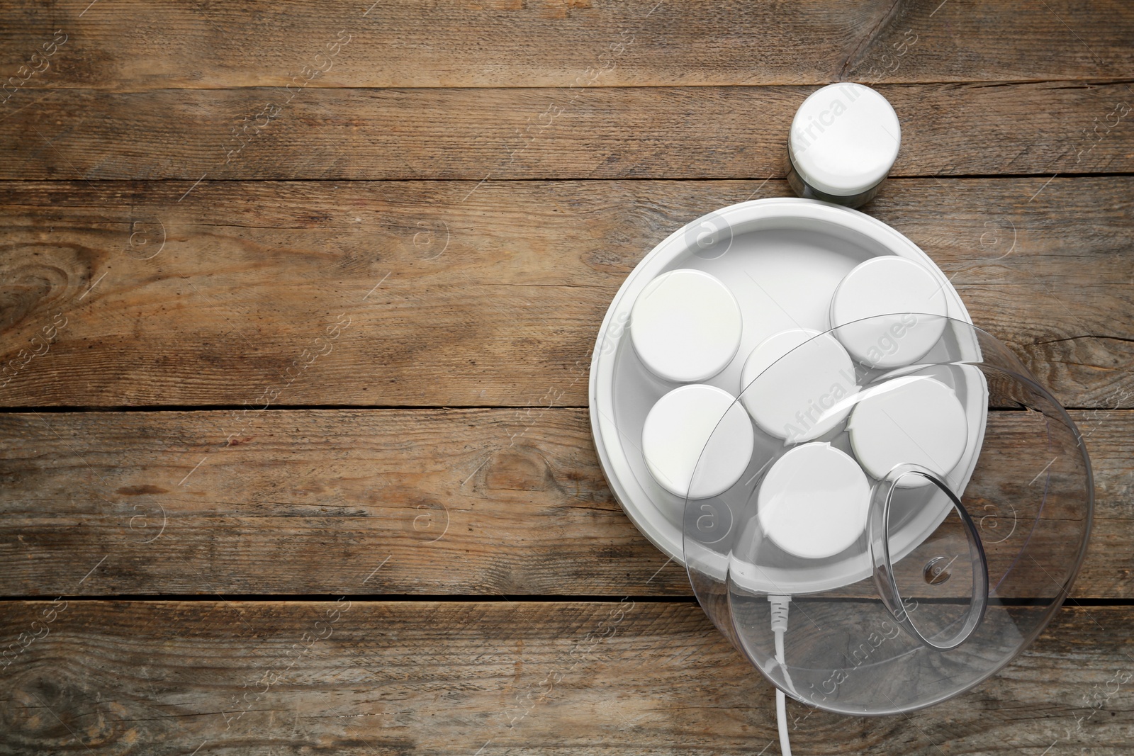 Photo of Modern yogurt maker with jars on wooden table, flat lay. Space for text