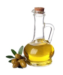 Photo of Glass jug of oil, ripe olives and leaves on white background