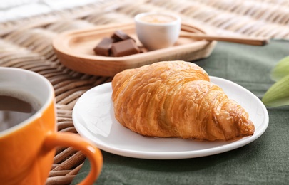 Photo of Plate with tasty freshly baked croissant on table