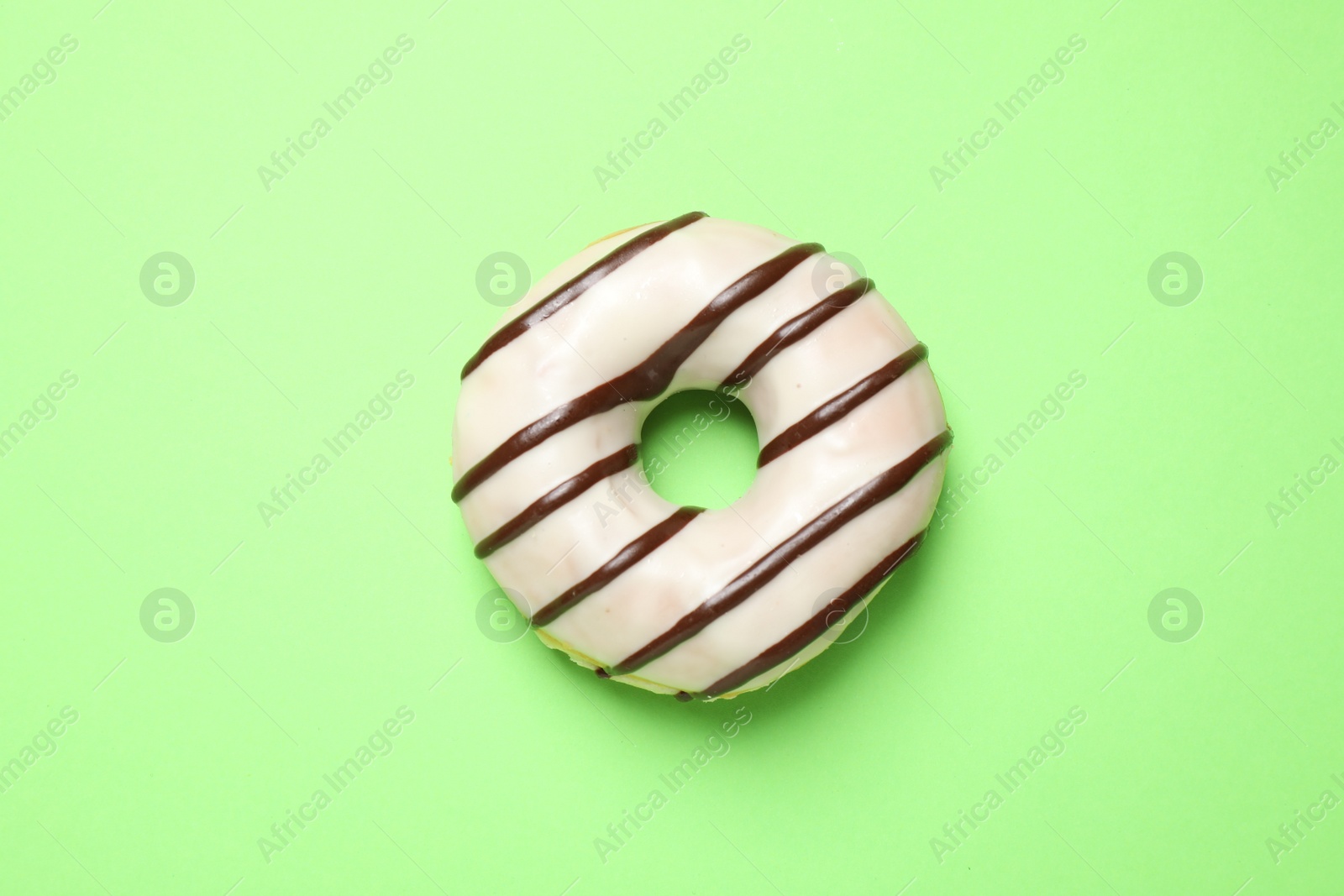 Photo of Delicious glazed donut on green background, top view