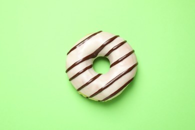 Delicious glazed donut on green background, top view
