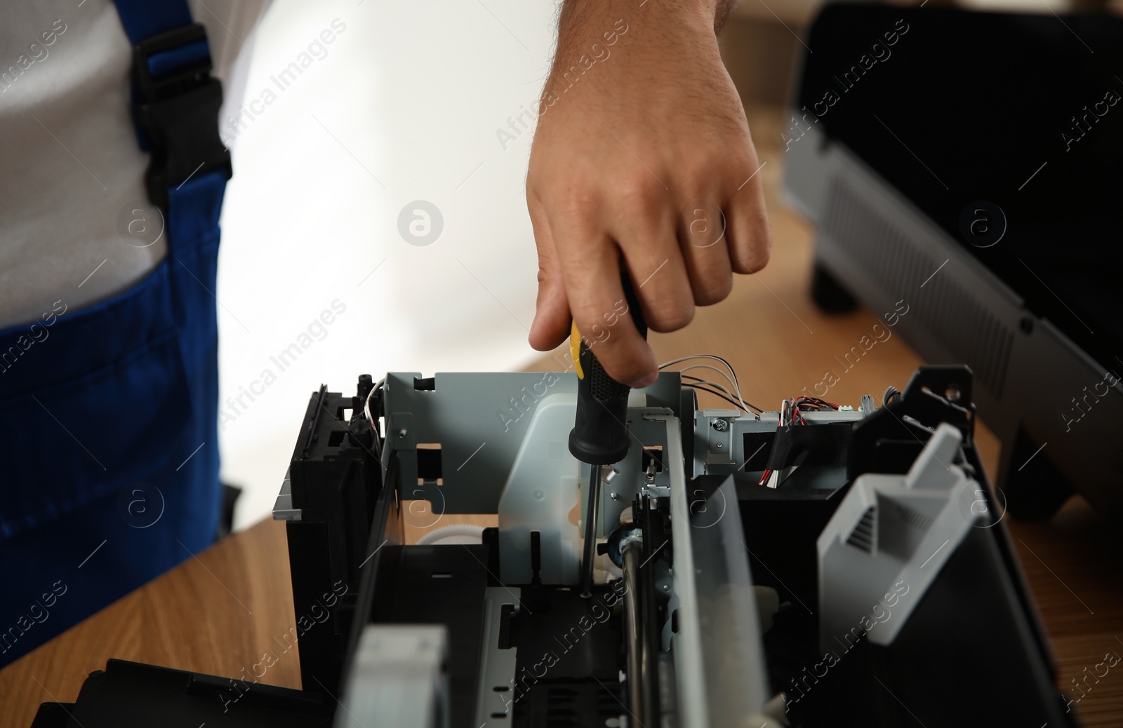 Photo of Repairman with screwdriver fixing modern printer indoors, closeup