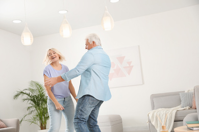 Happy mature couple dancing together in living room