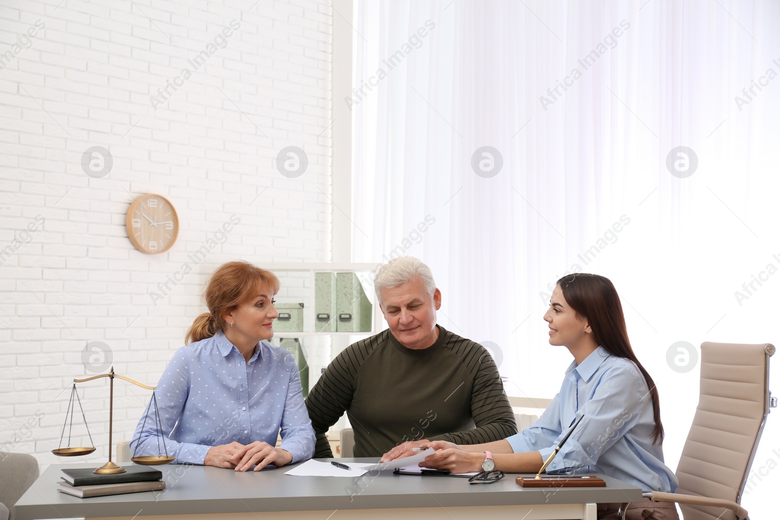 Photo of Young lawyer consulting senior couple in office