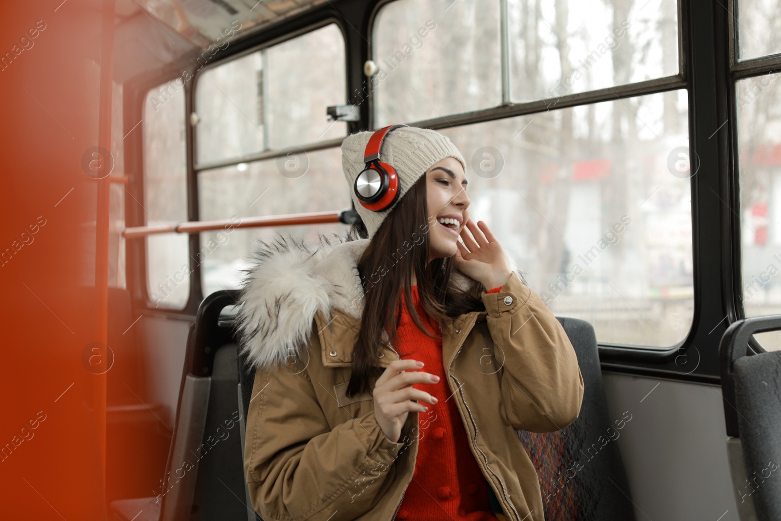 Photo of Young woman listening to music with headphones in public transport