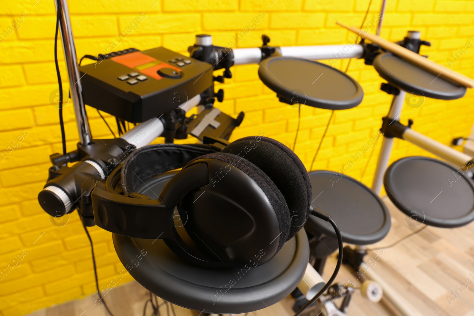 Photo of Modern electronic drum kit with headphones indoors. Musical instrument