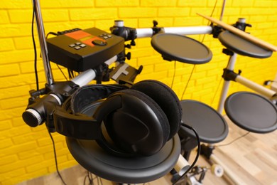 Photo of Modern electronic drum kit with headphones indoors. Musical instrument