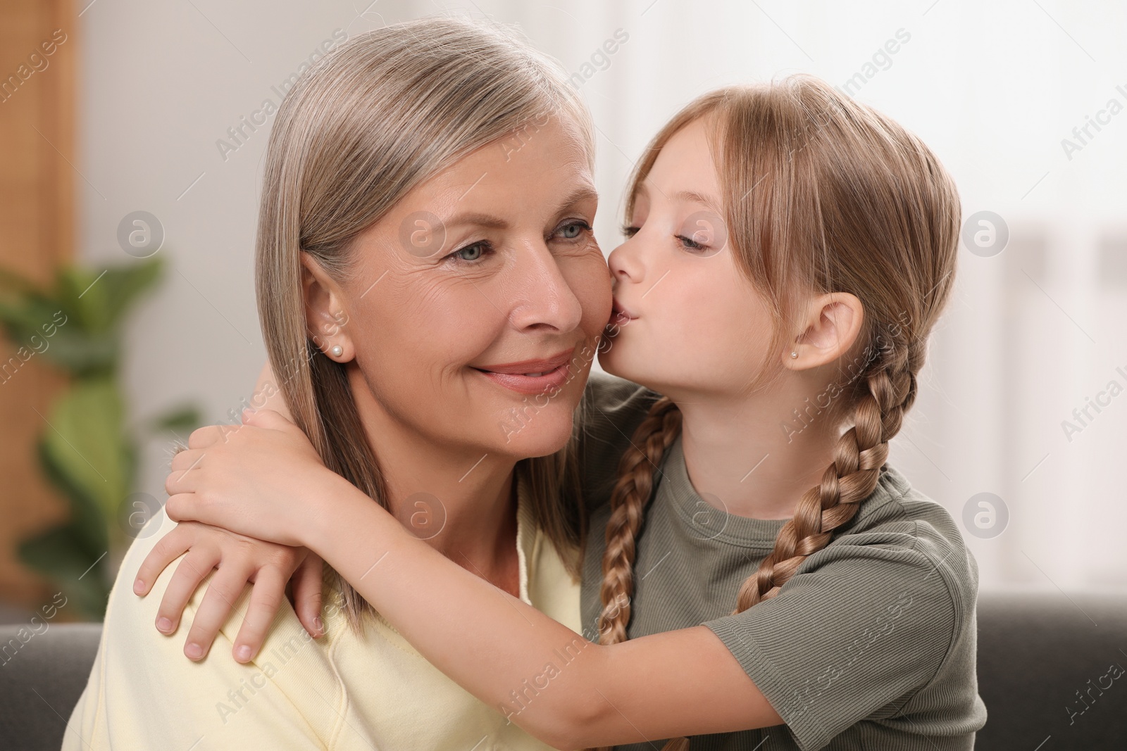 Photo of Happy granddaughter kissing her grandmother at home