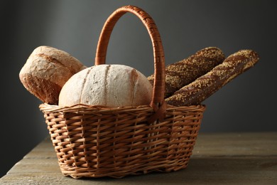 Photo of Wicker basket with different types of fresh bread on wooden table