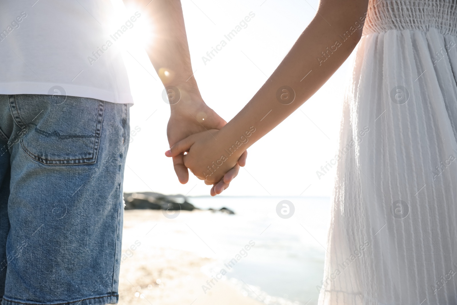 Photo of Young couple walking on beach, closeup. Honeymoon trip