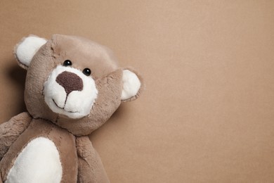 Cute teddy bear on brown background, top view. Space for text