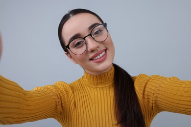 Photo of Smiling young woman taking selfie on grey background