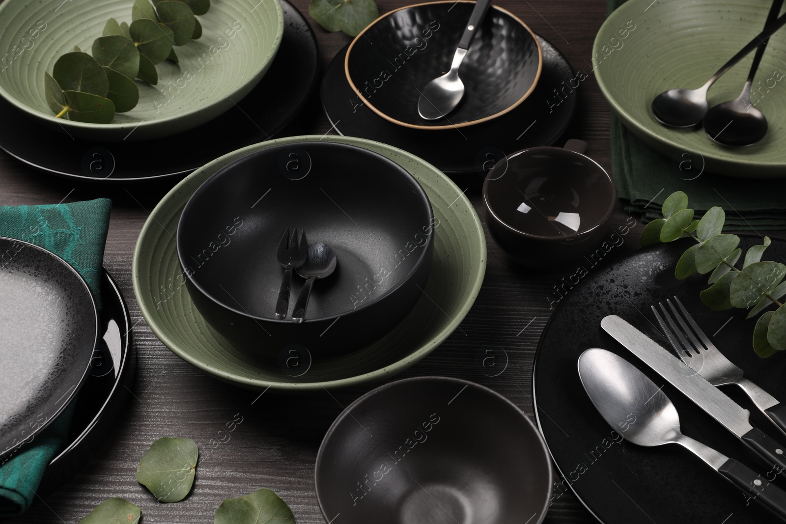 Photo of Stylish table setting with cutlery and eucalyptus branches on dark wooden background