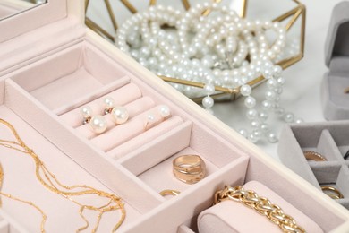 Photo of Jewelry boxes with many different accessories on white table, closeup
