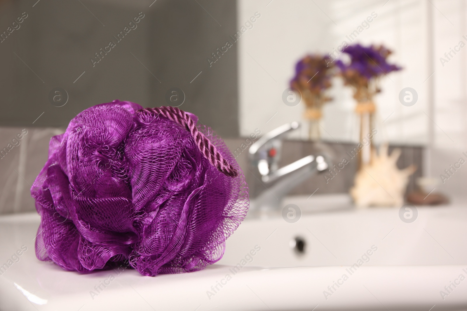 Photo of Purple shower puff on sink in bathroom, space for text