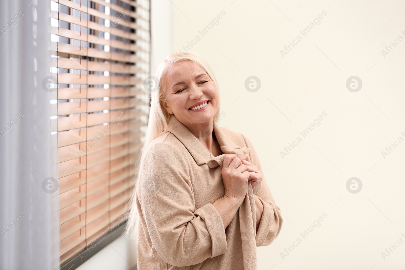 Photo of Portrait of happy mature woman near window indoors