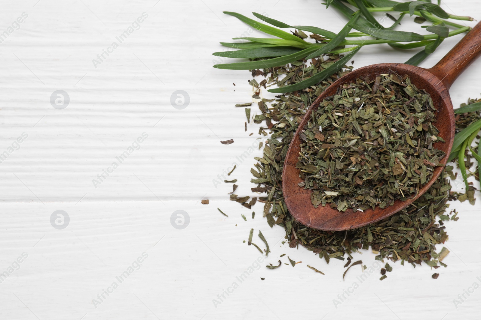 Photo of Spoon of dry tarragon and fresh leaves on white wooden table, flat lay. Space for text