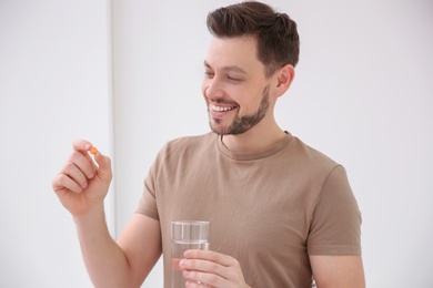 Photo of Young man taking vitamin indoors