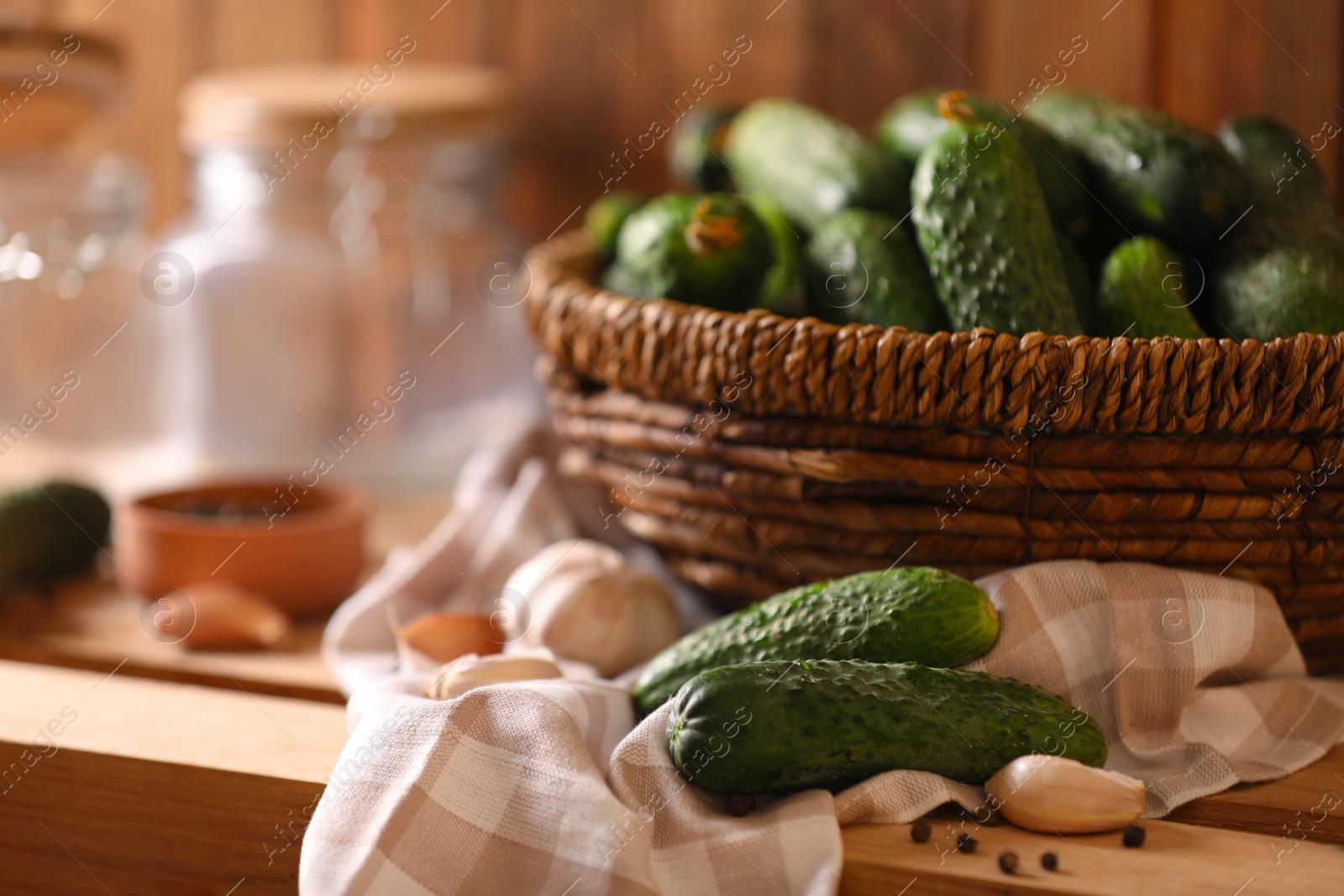 Photo of Fresh cucumbers and other ingredients prepared for canning on wooden table, closeup