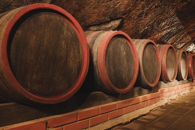 Photo of Many barrels of wine stored on shelf in cellar