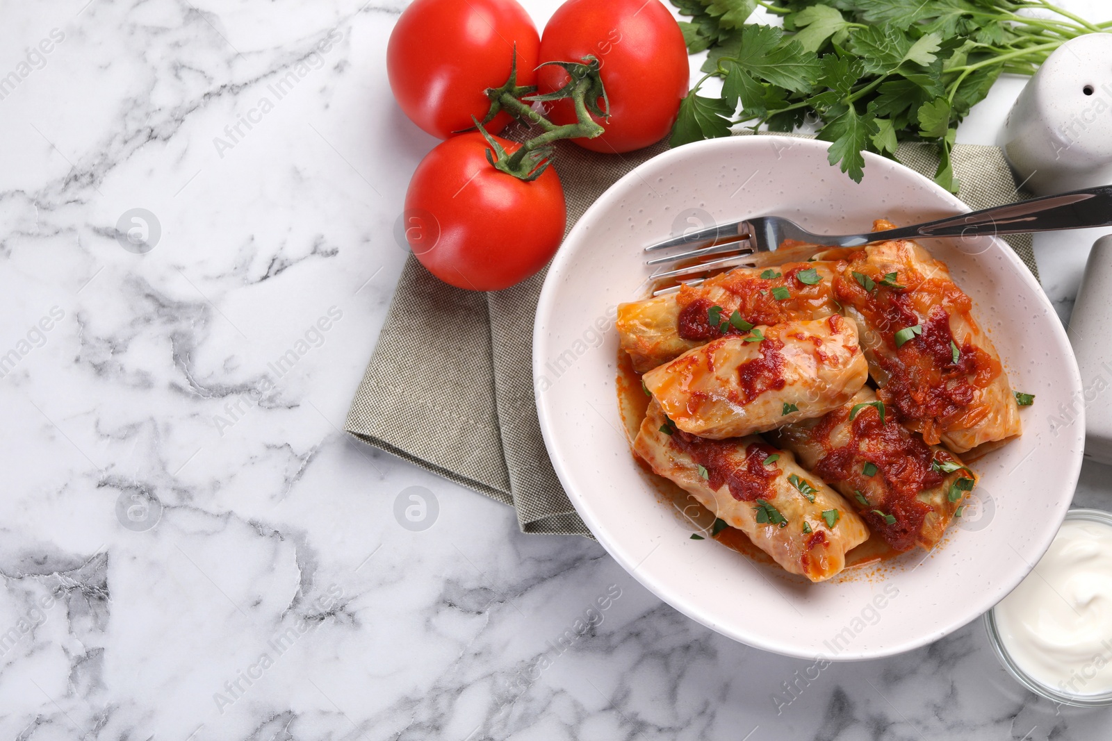 Photo of Delicious stuffed cabbage rolls cooked with homemade tomato sauce on white marble table, flat lay. Space for text