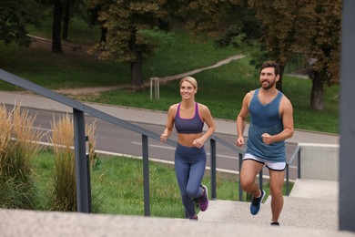 Photo of Healthy lifestyle. Happy couple running up stairs outdoors