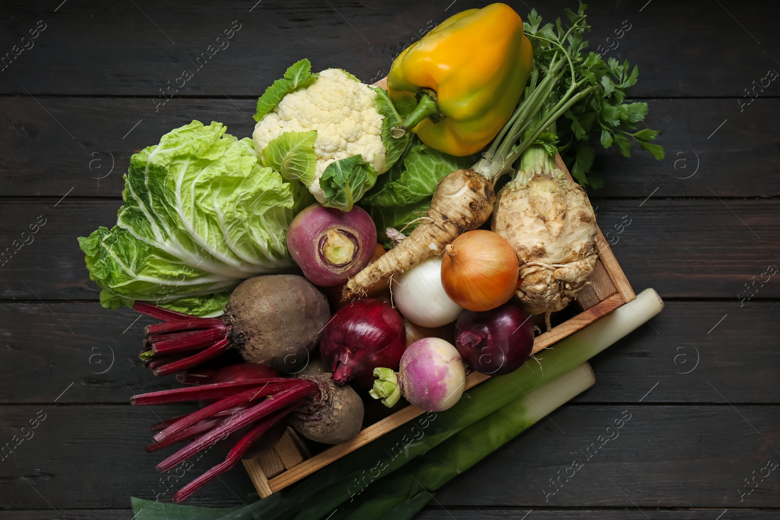 Photo of Crate full of different vegetables on black wooden table, top view. Farmer harvesting