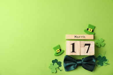 Photo of Flat lay composition with block calendar on light green background, space for text. St. Patrick's Day celebration