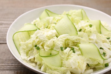 Tasty salad with Chinese cabbage, cucumber and green onion in bowl on wooden table, closeup