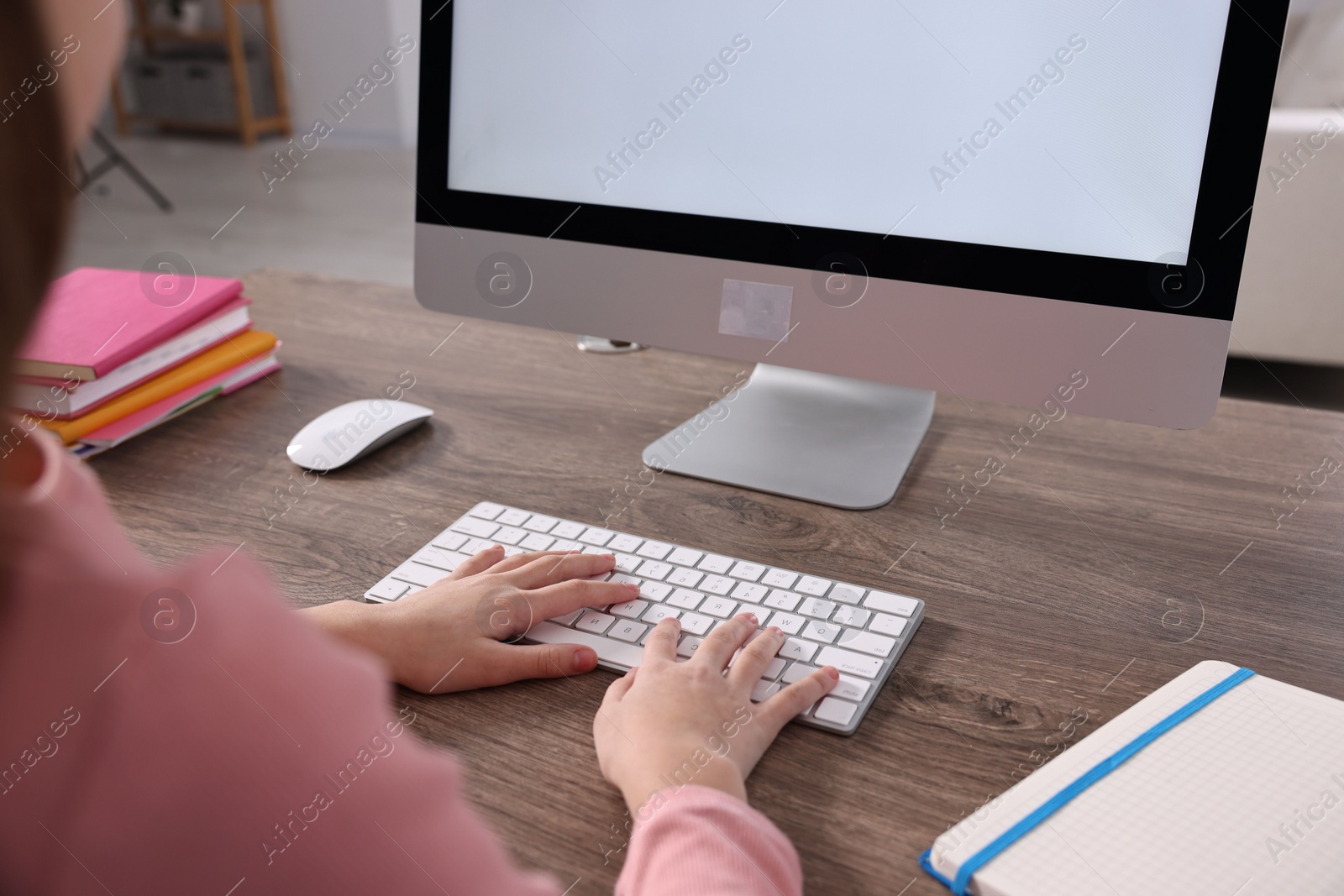 Photo of E-learning. Girl using computer during online lesson at table indoors, closeup