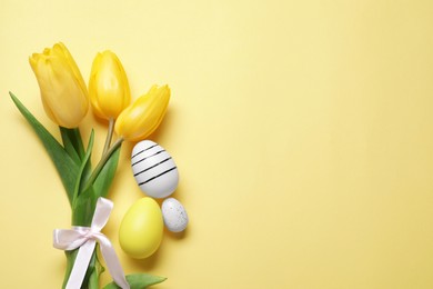 Photo of Flat lay composition with tulips and beautifully painted eggs on yellow background, space for text. Easter celebration