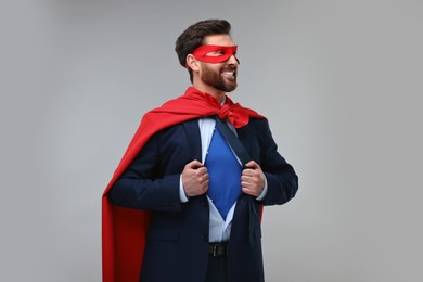 Photo of Happy businessman wearing superhero costume under suit on beige background