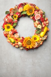 Photo of Beautiful autumnal wreath with flowers, berries and fruits on light grey background, top view. Space for text