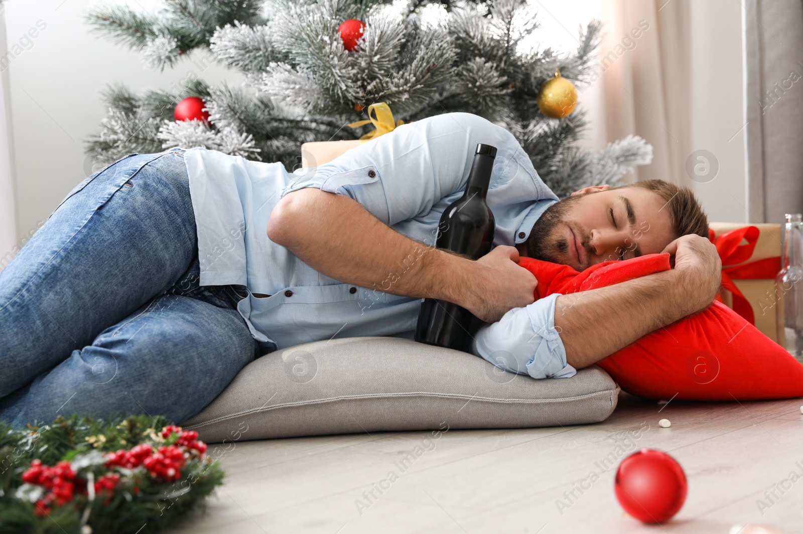 Photo of Drunk man sleeping on floor in messy room after New Year party