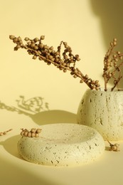 Presentation of product. Stone podium and vase with beautiful branches on yellow background