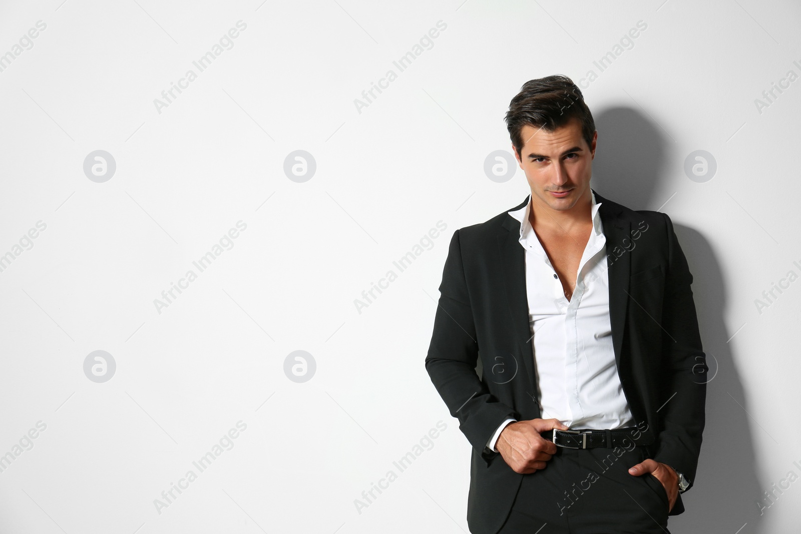 Photo of Handsome young man in elegant suit on light beige background. Space for text