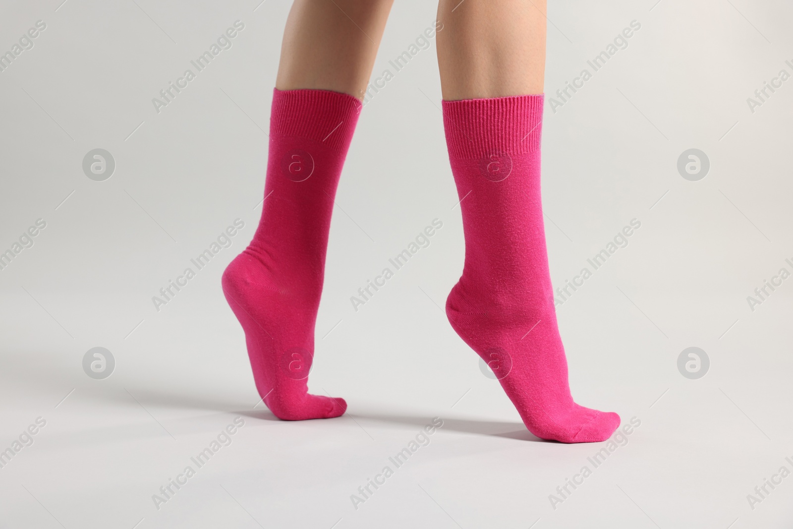 Photo of Woman in stylish bright pink socks on light grey background, closeup