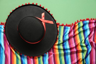 Mexican sombrero hat and colorful poncho on green background, flat lay