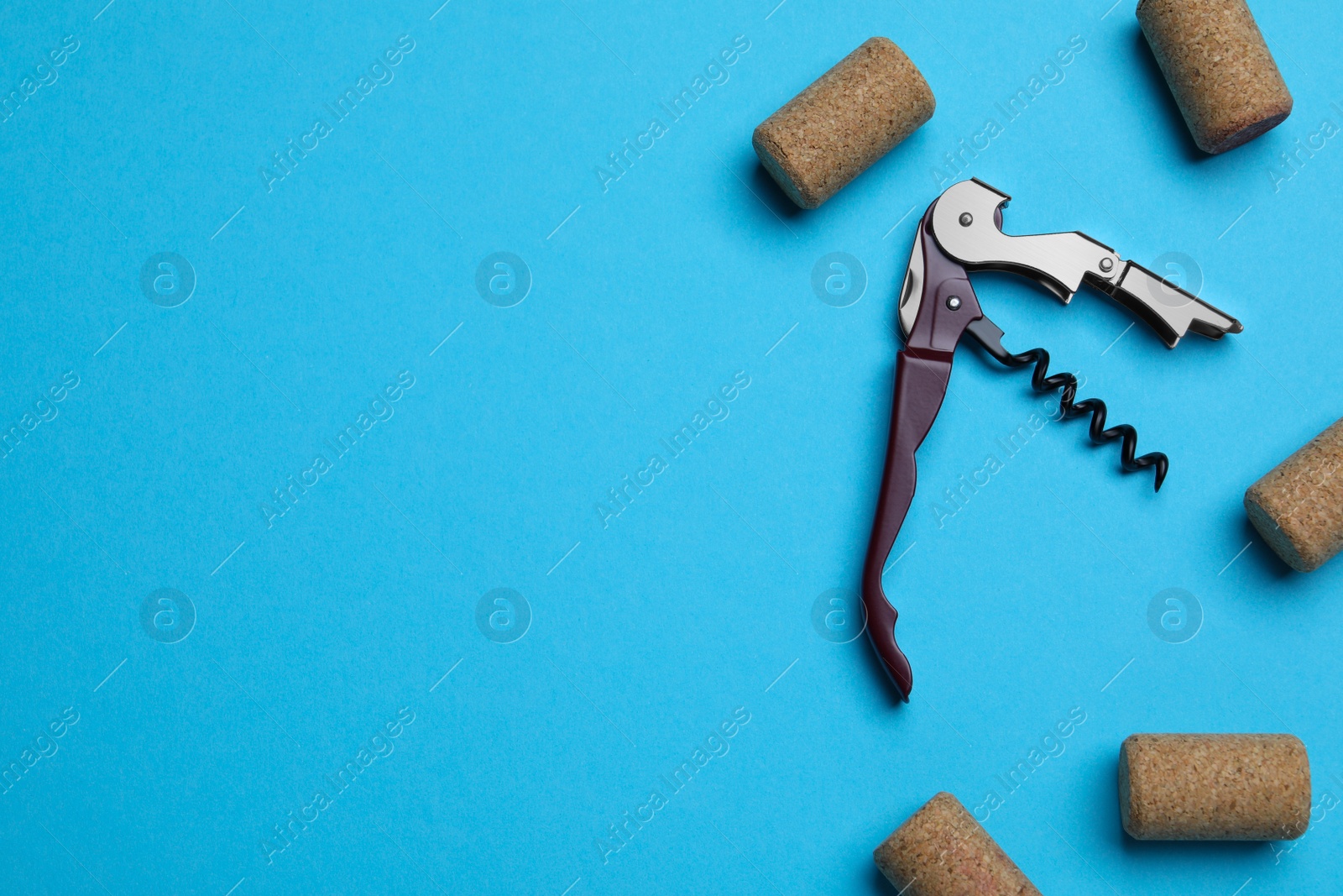 Photo of Corkscrew and wine bottle stoppers on turquoise background, flat lay. Space for text