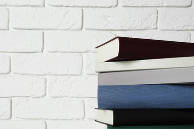 Photo of Stack of hardcover books near white brick wall, space for text