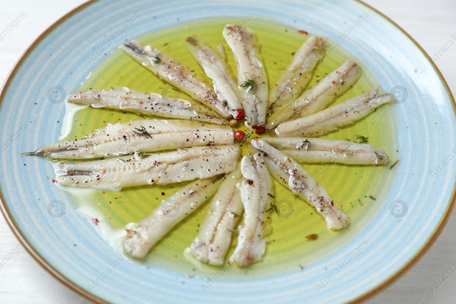 Photo of Tasty pickled anchovies with spices on table, closeup