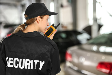 Image of Security guard using portable radio transmitter in automobile repair shop, space for text