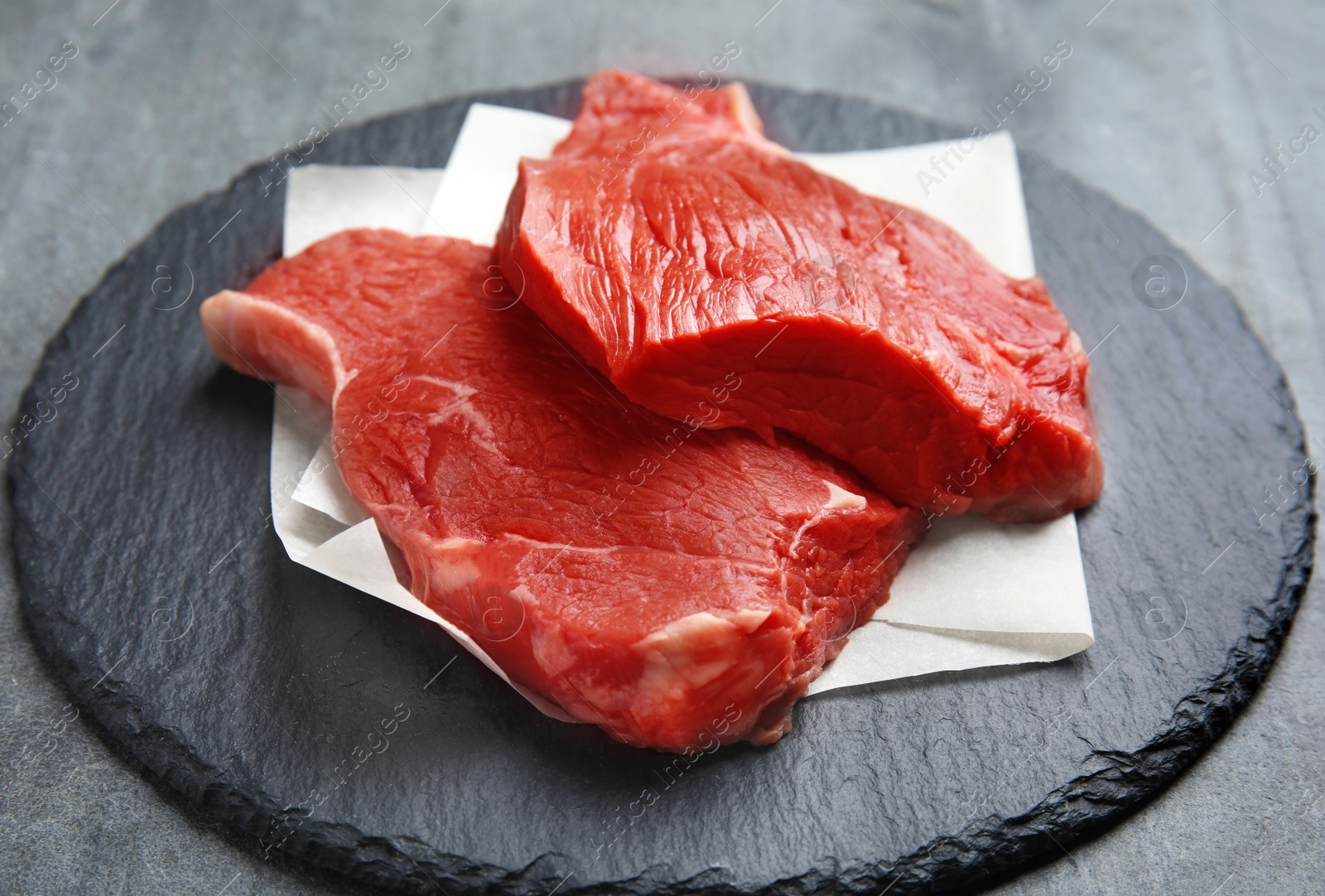 Photo of Fresh raw beef cut on grey table, closeup