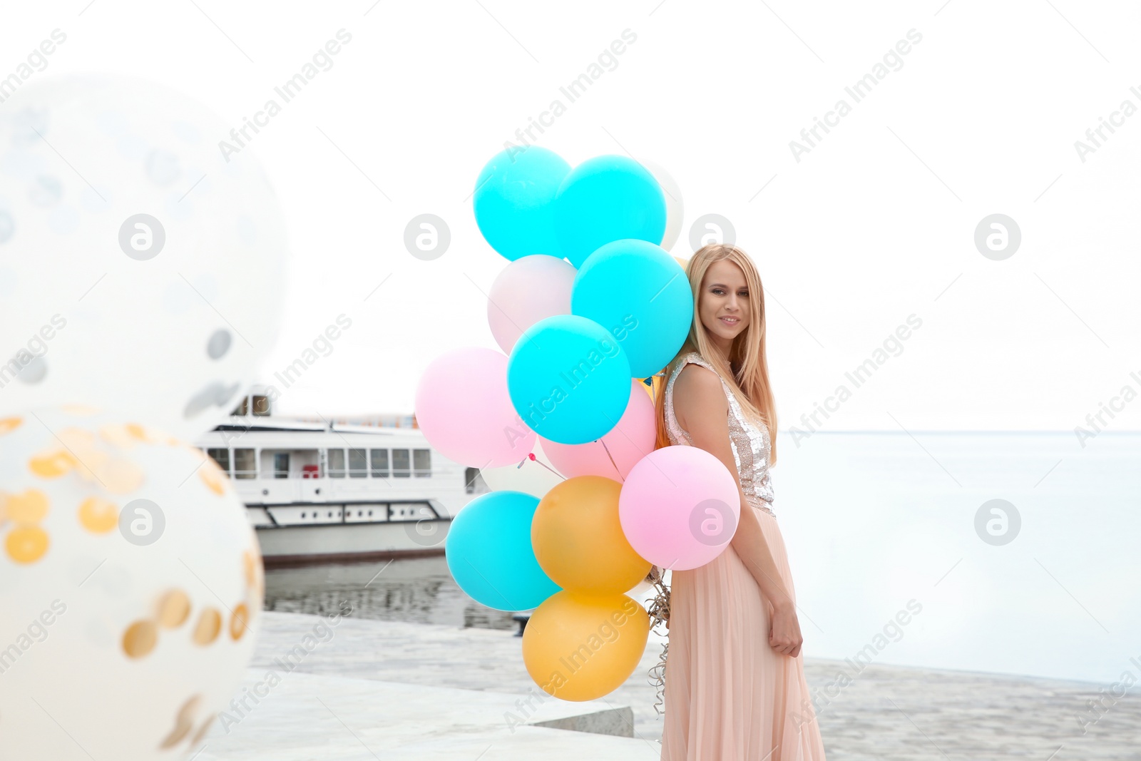 Photo of Beautiful young woman with bunch of balloons outdoors